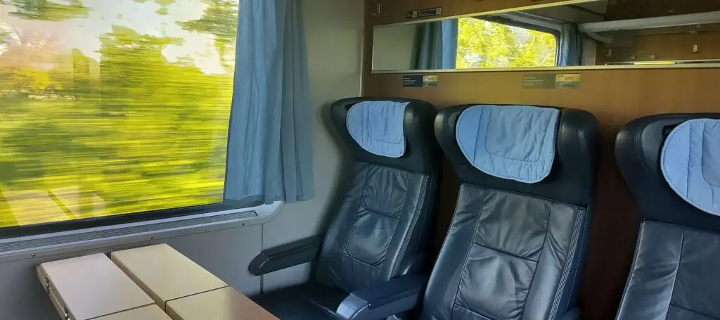 a first class cabin aboard an ICE train to Berlin with the landscape flashing by.
