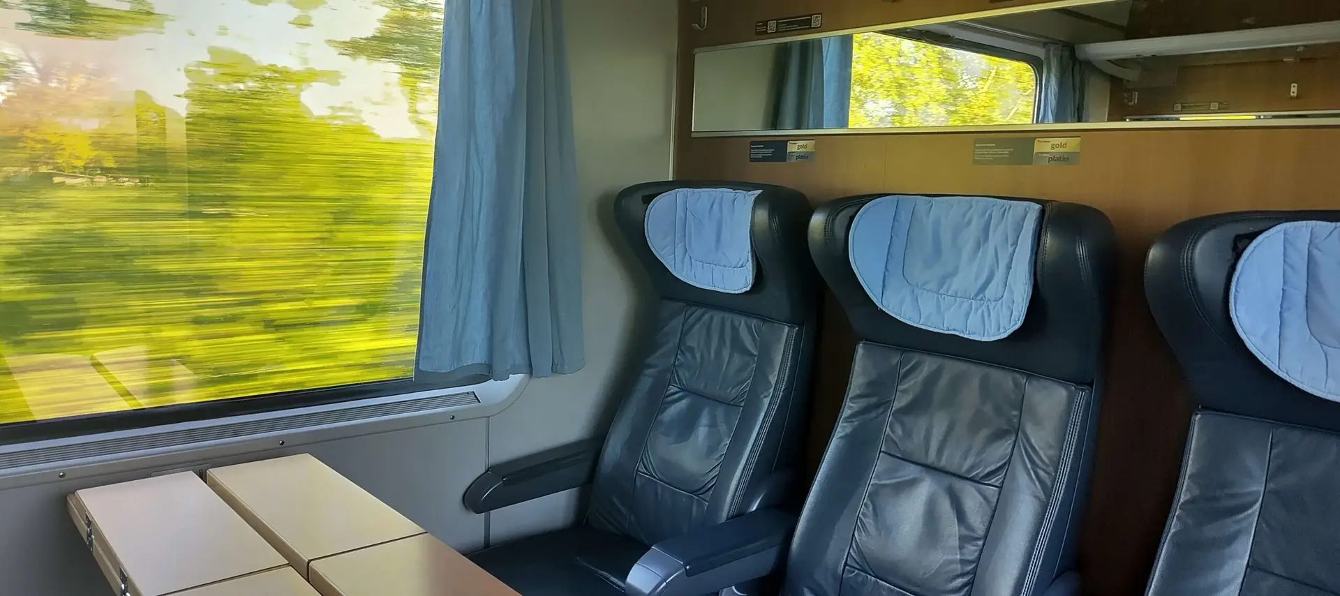 a first class cabin aboard an ICE train to Berlin with the landscape flashing by.