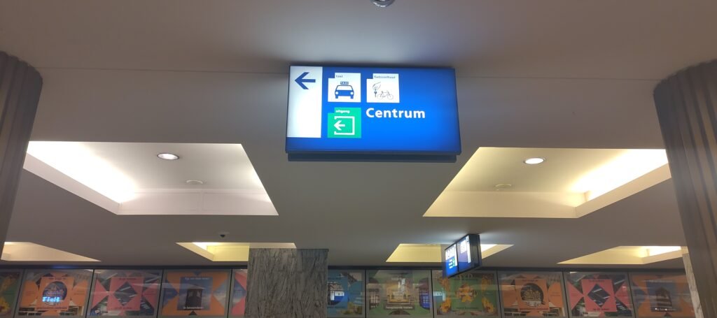 Blue lit up sign pointing towards the exit at the center side of the station